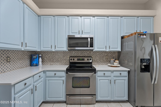 kitchen featuring tasteful backsplash, light tile patterned floors, and stainless steel appliances