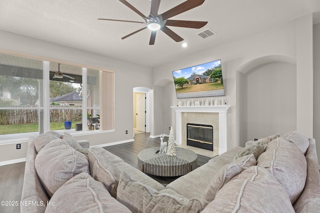 living room with ceiling fan, dark wood-type flooring, and a fireplace