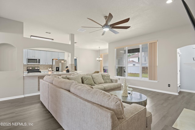 living room with dark hardwood / wood-style flooring and ceiling fan with notable chandelier