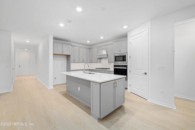 kitchen featuring sink, gray cabinetry, stainless steel appliances, an island with sink, and custom exhaust hood