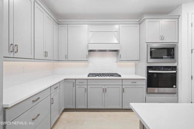 kitchen with gray cabinetry, backsplash, and appliances with stainless steel finishes