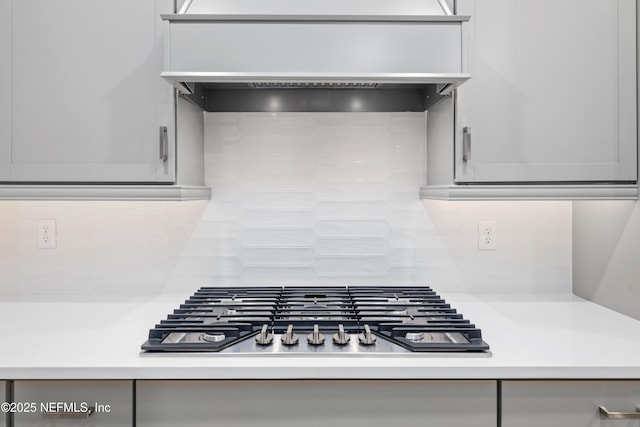 kitchen featuring stainless steel gas cooktop, decorative backsplash, and wall chimney range hood