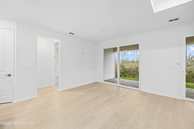 spare room with a skylight and light wood-type flooring