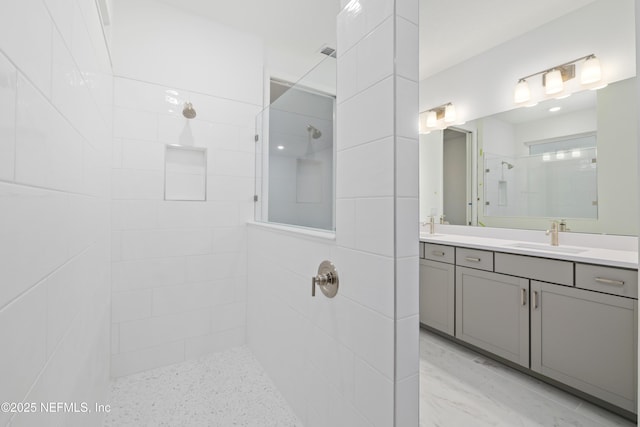 bathroom with tiled shower and vanity