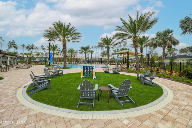 view of community featuring a swimming pool, a lawn, a playground, and a patio area