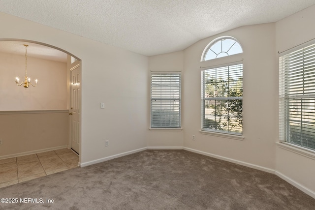 carpeted empty room with vaulted ceiling, a chandelier, and a textured ceiling