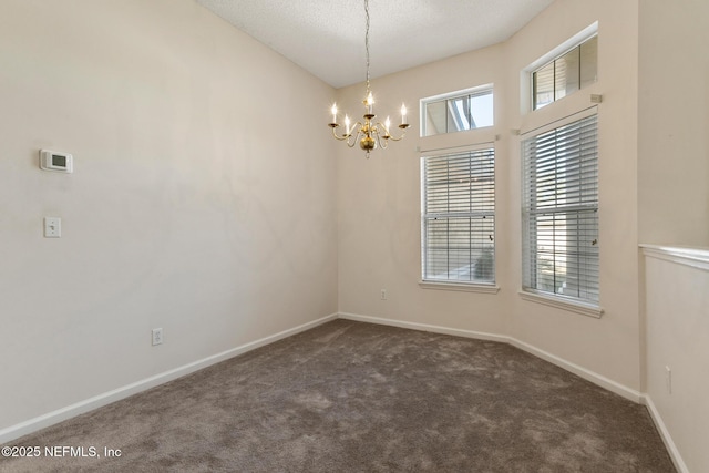 carpeted spare room featuring a textured ceiling and an inviting chandelier