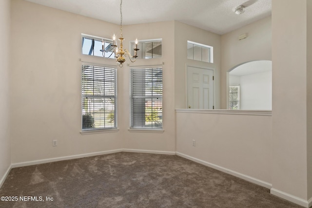 empty room with a towering ceiling, a chandelier, and dark carpet