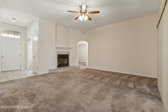 unfurnished living room featuring ceiling fan, light colored carpet, a textured ceiling, and a fireplace