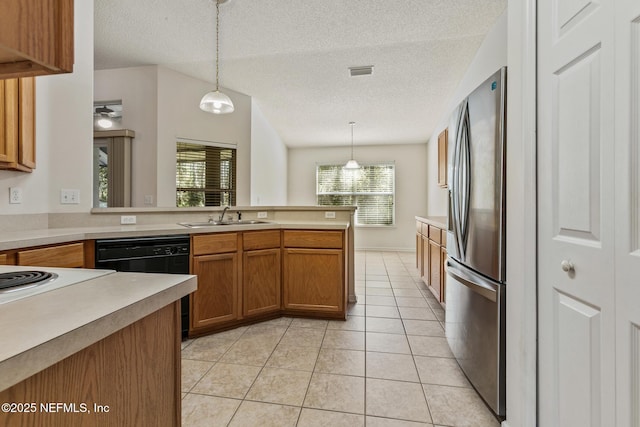 kitchen with sink, a textured ceiling, stainless steel fridge, black dishwasher, and pendant lighting