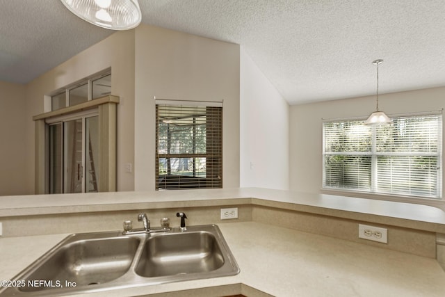 kitchen with decorative light fixtures, sink, and a textured ceiling