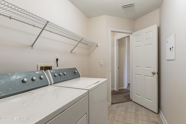 laundry area with washing machine and clothes dryer and a textured ceiling