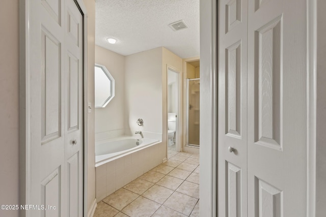 bathroom featuring tile patterned floors, toilet, a textured ceiling, and plus walk in shower