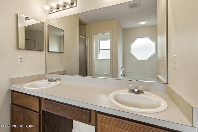 bathroom featuring vanity, a shower with shower door, and a textured ceiling