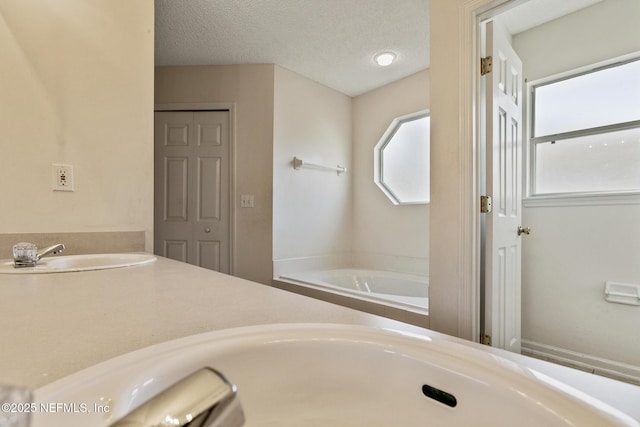 bathroom with vanity, a bathtub, and a textured ceiling