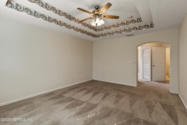 carpeted empty room with a raised ceiling, a textured ceiling, and ceiling fan