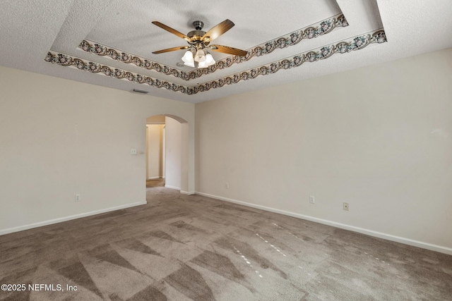 spare room with a tray ceiling, a textured ceiling, ceiling fan, and carpet flooring