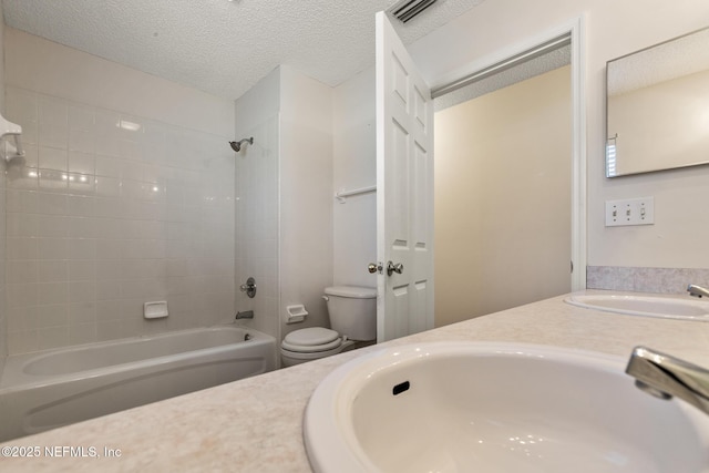 full bathroom featuring vanity, toilet, tiled shower / bath combo, and a textured ceiling