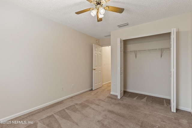 unfurnished bedroom with a closet, ceiling fan, light colored carpet, and a textured ceiling