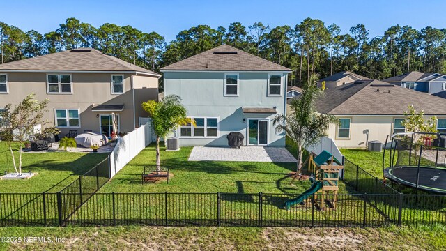 rear view of house featuring a playground, central AC, a yard, and a trampoline