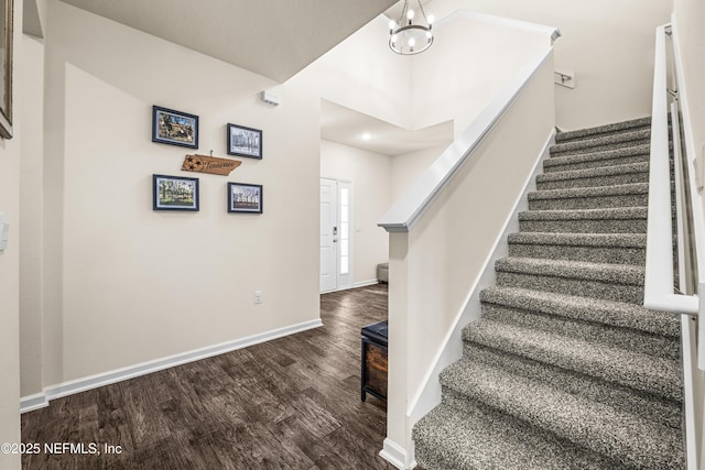 stairs with wood-type flooring and a chandelier