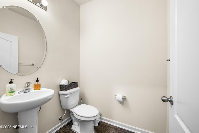 bathroom with toilet, hardwood / wood-style floors, and sink