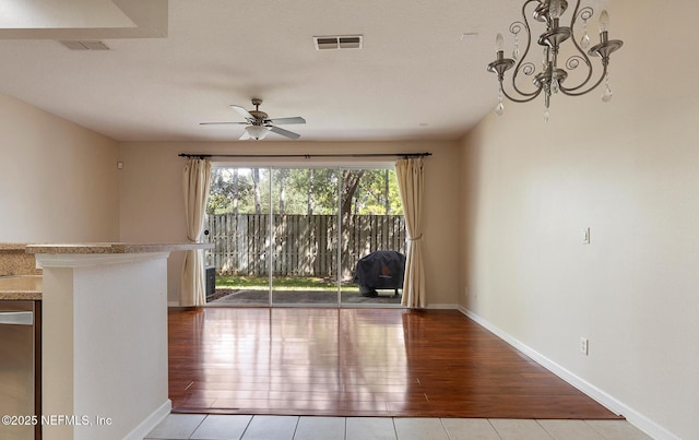 unfurnished room featuring ceiling fan with notable chandelier and light hardwood / wood-style flooring