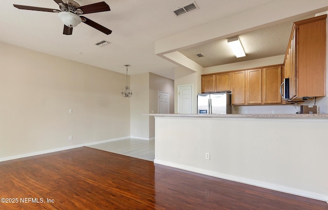 kitchen featuring ceiling fan, stainless steel fridge with ice dispenser, a textured ceiling, and light hardwood / wood-style flooring