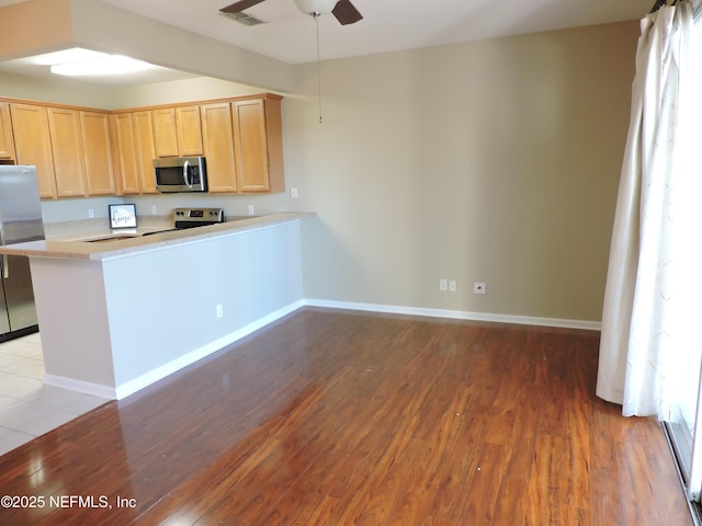 kitchen featuring hardwood / wood-style floors, kitchen peninsula, ceiling fan, stainless steel appliances, and light brown cabinets