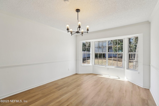 unfurnished dining area featuring a textured ceiling, an inviting chandelier, a wealth of natural light, and hardwood / wood-style flooring