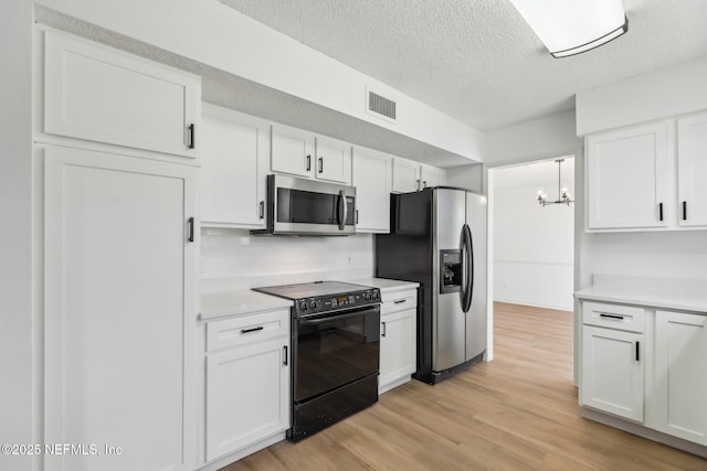 kitchen featuring appliances with stainless steel finishes, white cabinetry, an inviting chandelier, decorative backsplash, and light hardwood / wood-style floors