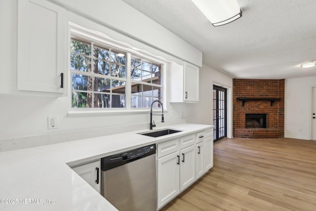 kitchen with stainless steel dishwasher, plenty of natural light, sink, and white cabinetry