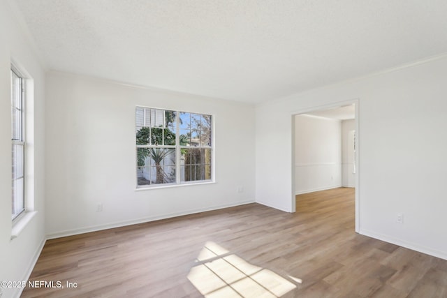 empty room with a textured ceiling and light wood-type flooring