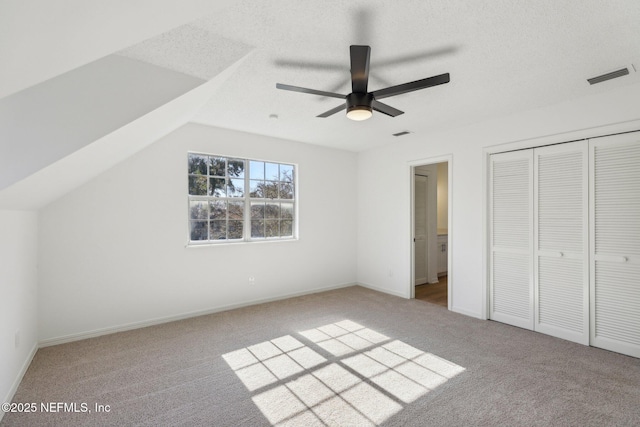 unfurnished bedroom with ceiling fan, light colored carpet, a closet, and lofted ceiling