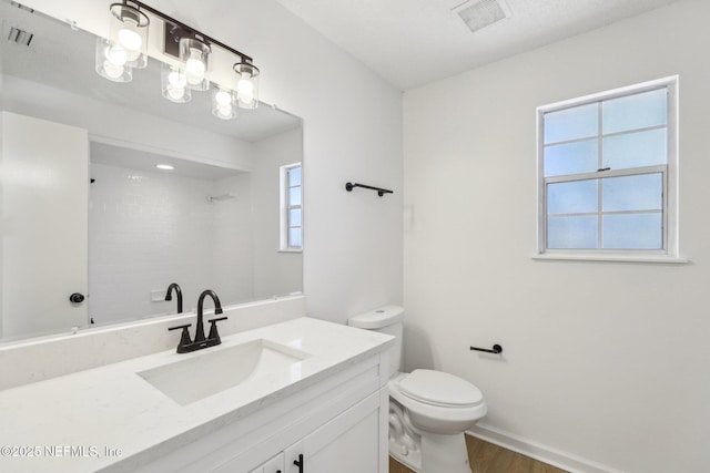 bathroom featuring toilet, a healthy amount of sunlight, wood-type flooring, and vanity