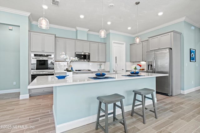 kitchen with a large island, hanging light fixtures, gray cabinetry, and stainless steel appliances