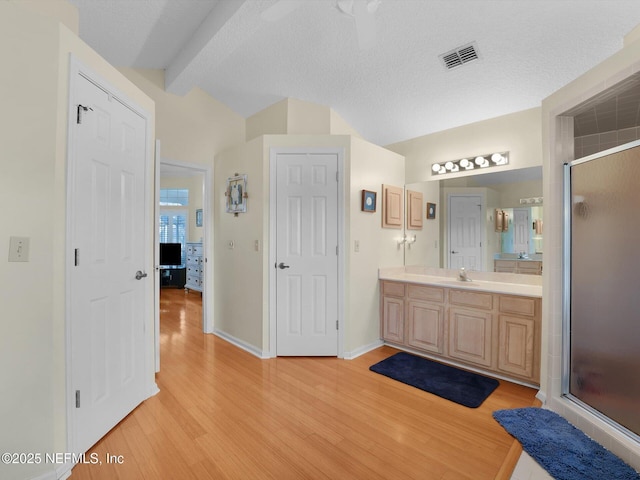 bathroom featuring vanity, hardwood / wood-style flooring, an enclosed shower, and lofted ceiling with beams