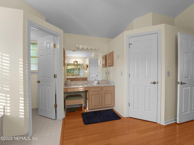 bathroom with a textured ceiling, wood-type flooring, and vanity