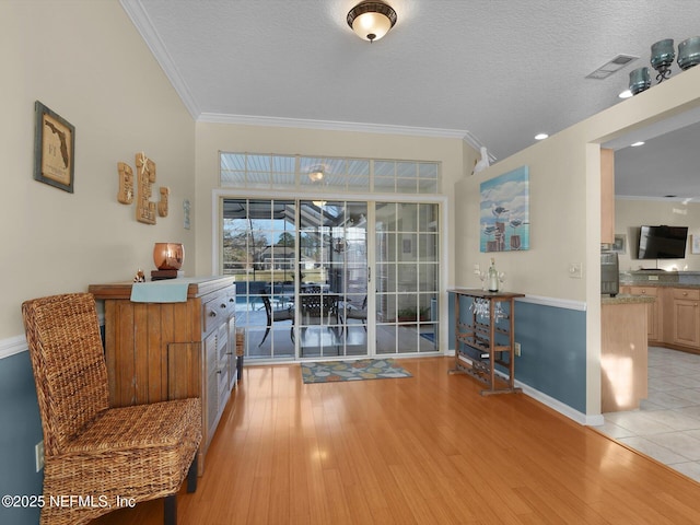 interior space with crown molding, a textured ceiling, and light hardwood / wood-style floors