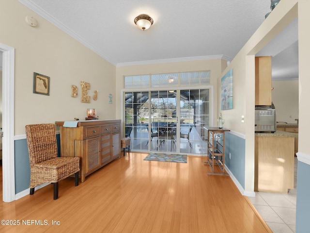 living area with a textured ceiling, light hardwood / wood-style flooring, crown molding, and cooling unit