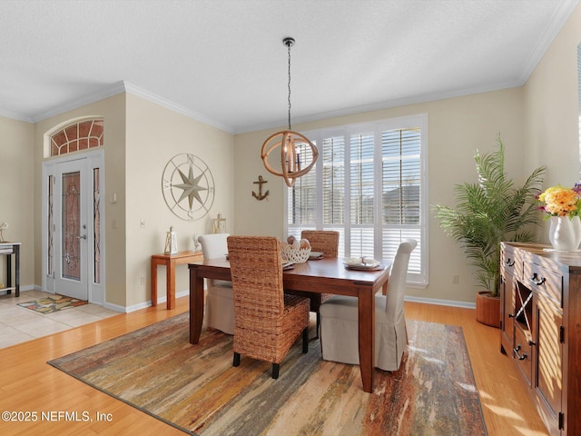 dining area featuring a textured ceiling, ornamental molding, an inviting chandelier, and light wood-type flooring