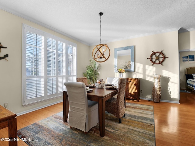 dining room with hardwood / wood-style flooring, a textured ceiling, ornamental molding, and an inviting chandelier