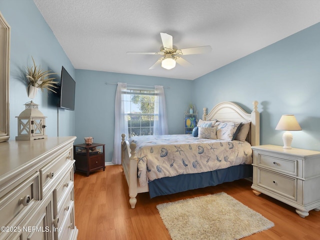 bedroom with ceiling fan, light wood-type flooring, and a textured ceiling