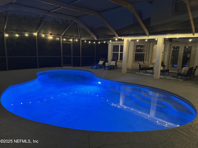 pool at twilight featuring french doors, ceiling fan, a lanai, and a patio area