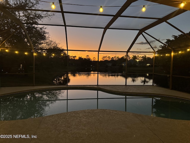 pool at dusk featuring a water view and glass enclosure