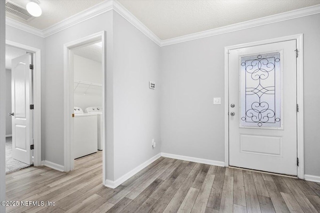 foyer entrance with a textured ceiling, separate washer and dryer, and light hardwood / wood-style floors