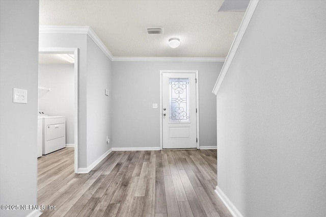 entryway with a textured ceiling, crown molding, light hardwood / wood-style floors, and washer / clothes dryer