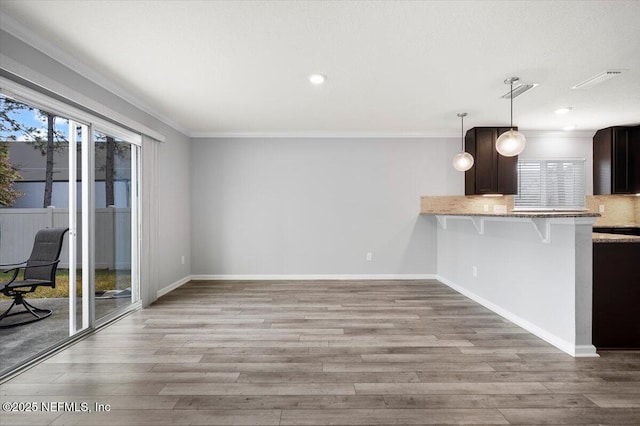 kitchen with decorative light fixtures, a wealth of natural light, and ornamental molding