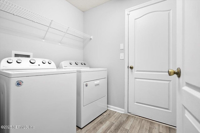 laundry room with separate washer and dryer and light hardwood / wood-style floors