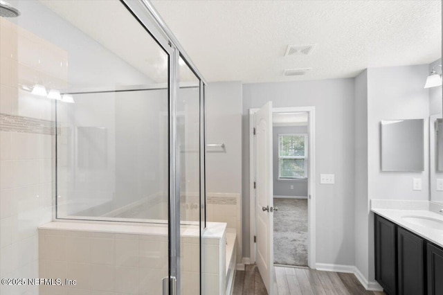 bathroom with vanity, a textured ceiling, and a shower with door